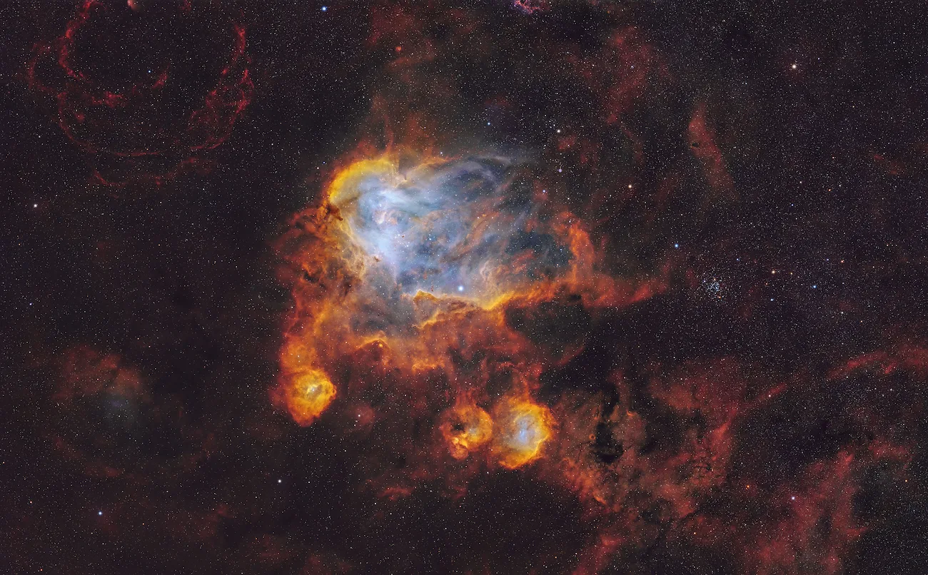 An image showing the bright glowing clouds and sweeping shapes of the Running Chicken Nebula set against a field of stars